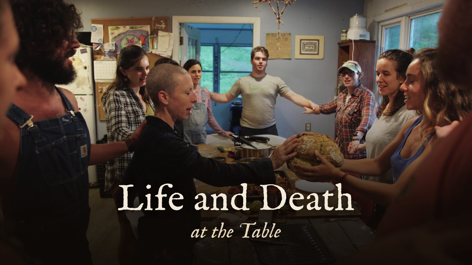 Life and Death at the Table title card: a community gathered around a table, hands on a loaf of bread